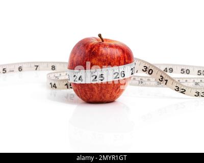 Faites le choix sain. Studio photo d'une pomme rouge avec du ruban de mesure enroulé autour de lui. Banque D'Images