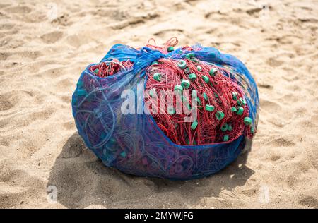 Filets de pêche recueillis sur la plage de sable. grande balle de filets de pêche. filets de pêche en nylon sur la plage Banque D'Images