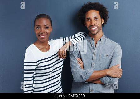Ils font un beau couple. Portrait d'un jeune couple heureux sur fond gris. Banque D'Images