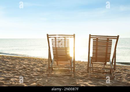 Chaises longues en bois sur une plage de sable. Vacances d'été Banque D'Images