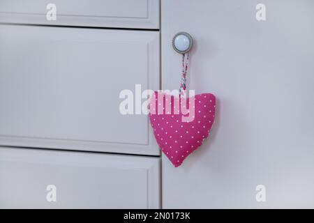 Coeur en tissu fait main. Coeur en tissu de scrim suspendu sur la commode en bois blanc. Décorations de Saint-Valentin. Concept d'amour Banque D'Images