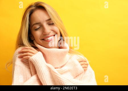 Belle jeune femme portant un pull tricoté sur fond jaune. Espace pour le texte Banque D'Images