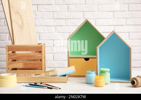 Composition avec étagères en forme de maison et pots de peintures sur la table contre le mur de brique. Éléments intérieurs Banque D'Images