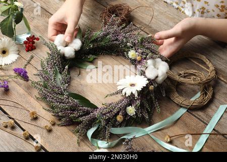 Fleuriste faisant belle couronne automnale avec des fleurs chinées à table en bois, gros plan Banque D'Images