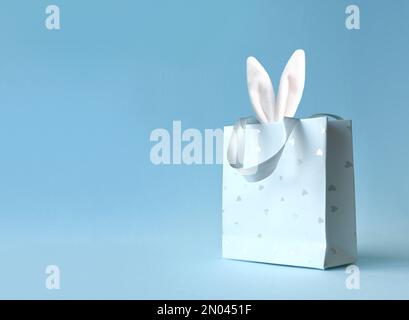 Oreilles de lapin de Pâques dans un sac en papier. Arrière-plan bleu. Espace pour le texte. Joyeuses pâques Banque D'Images