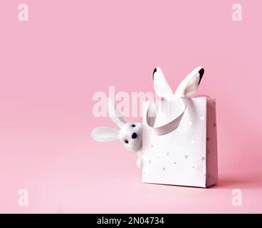 Oreilles de lapin de Pâques dans un sac en papier. Fond rose. Espace pour le texte. Joyeuses pâques Banque D'Images