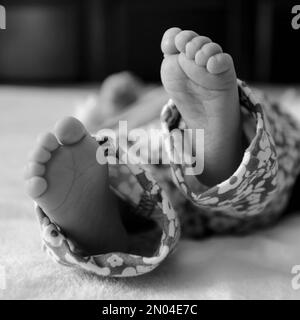 Un cliché noir et blanc des pieds d'un nouveau-né sur un arrière-plan flou Banque D'Images