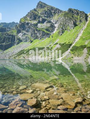 Montagne rocheuse proéminente se reflétant dans un lac alpin clair en cristal, plan vertical, Pologne, UE Banque D'Images