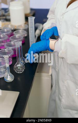 Gros plan d'un chercheur utilisant une montre intelligente dans un laboratoire. Banque D'Images