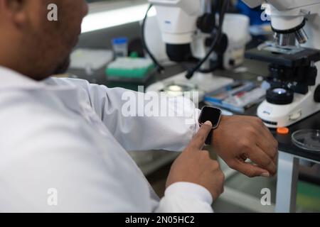 Gros plan d'un chercheur utilisant une montre intelligente dans un laboratoire. Banque D'Images