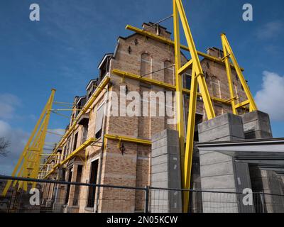 Soutenir les piliers et les contrepoids contre un grand complexe de logements pour garantir la sécurité des travaux de démolition Banque D'Images