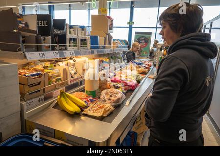 Une dame attend au moment du départ dans un supermarché Lidl avec des articles d'épicerie Banque D'Images