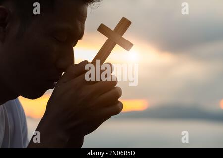 La main humaine tient la croix. Eucharistie la thérapie bénir Dieu aidant à se repentir Catholique Pâques Carême prier. Fond de concept chrétien. Banque D'Images