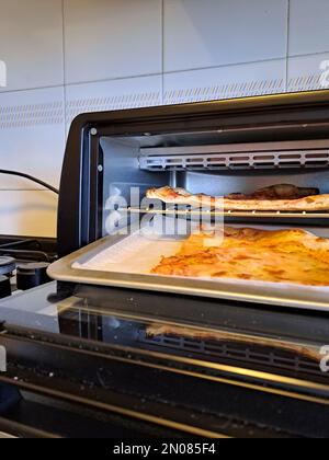 Tranche de pizza au fromage gros plan la vie réelle dans la cuisine, réchauffez dans le four électrique Banque D'Images