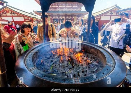 Tokyo, le célèbre sanctuaire d'Asakusa et temple Sensoji. Close up, les gens autour du grand brûleur en agitant la fumée au-dessus d'eux-mêmes. Banque D'Images