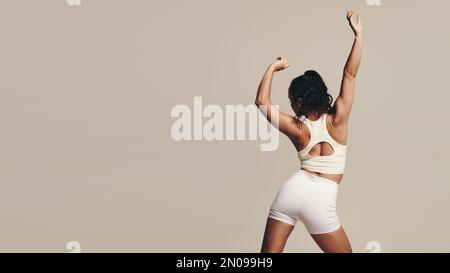 Faire tenir une femme debout dans un studio dans des vêtements de sport, faisant des mouvements de muscle-tonifiant corps dans le cadre de sa technique d'entraînement. Amélioration de la jeune athlète féminine Banque D'Images