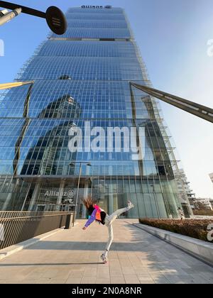 Une image fantastique d'une jeune fille, dansant dans des vêtements à la mode, sous la tour CityLife Allianz, la tour Isozaki, CityLife, Milan, Italie Banque D'Images