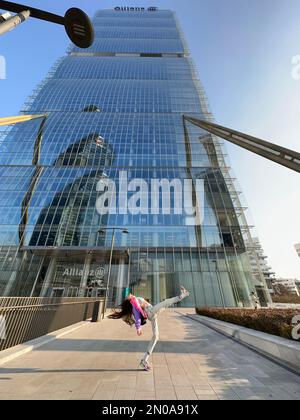 Une image fantastique d'une jeune fille, dansant dans des vêtements à la mode, sous la tour CityLife Allianz, la tour Isozaki, CityLife, Milan, Italie Banque D'Images