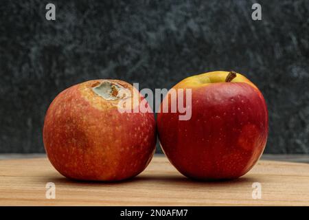 Une pomme pourrie à la moisissure et une pomme fraîche sur fond sombre Banque D'Images