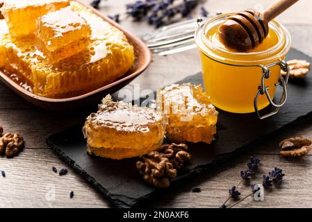 Nid d'abeille sur plateau en ardoise avec miel et noix sur la table de cuisine Banque D'Images