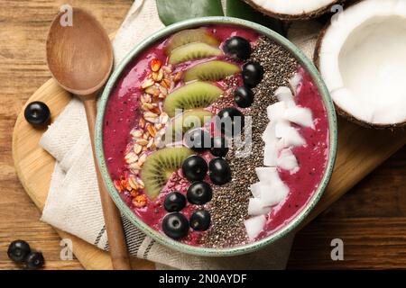 Délicieux smoothie d'acai et fruits dans un bol servi sur une table en bois, plat Banque D'Images