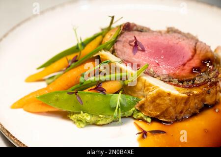 Bœuf Wellington aux carottes et haricots verts sautés, plaqué sur un plat blanc Banque D'Images
