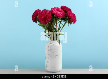 Beaux dessous de verre dans un vase sur une table sur fond bleu clair. Fleurs d'automne Banque D'Images