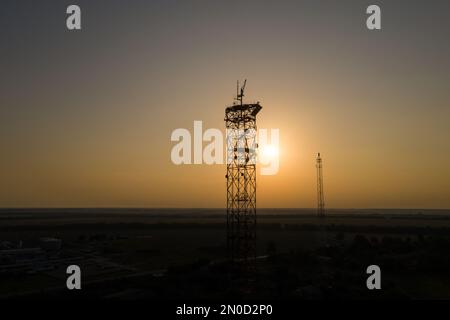 Le soleil brille à travers la silhouette des tours de télécommunication Banque D'Images