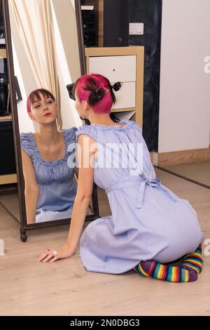 une adolescente regarde dans le miroir à l'intérieur, assise sur le sol Banque D'Images