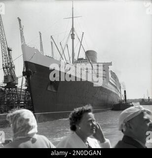 1950s, historique, RMS Queen Elizabeth amarré dans les docks de Southampton, Hampshire, Angleterre, Royaume-Uni. Exploité par la Cunard Line, le luxueux paquebot navigue chaque semaine de Southampton, Angleterre, Royaume-Uni à New York, États-Unis, via Cherbourg, en France. Construite par John Brown & Co sur le Clyde en Écosse, elle a été nommée en l'honneur de la reine Elizabeth, plus tard la reine mère. Lorsqu'elle a été lancée en 1938, elle était le plus grand navire à passagers jamais construit, restant ainsi jusqu'en 1994. Banque D'Images