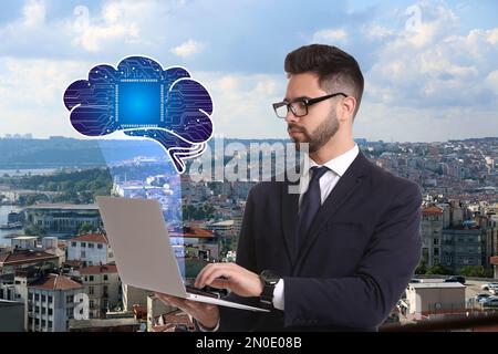 Jeune homme utilisant un ordinateur portable avec une image virtuelle du cerveau et du paysage urbain en arrière-plan. Concept d'apprentissage machine Banque D'Images