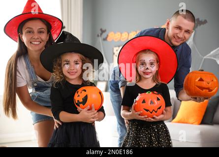 Bonne famille avec des seaux de bonbons d'Halloween et une lanterne de citrouille à tête de citrouille à la maison Banque D'Images