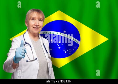 Brésilienne souriante mature médecin femme tenant le stéthoscope sur le drapeau du Brésil fond Banque D'Images