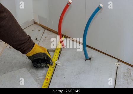 Préparation de la pose de carreaux de sol un entrepreneur mesurant les carreaux de céramique avant des couper Banque D'Images