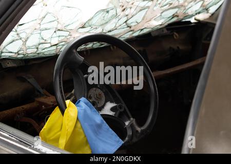 Un véhicule militaire tiré et le drapeau de l'Ukraine sur le volant se tient en Ukraine dans la rue, un véhicule militaire soufflé 2023 Banque D'Images