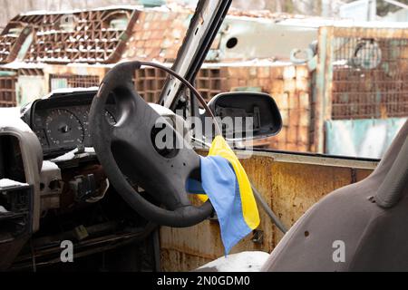 Un véhicule militaire tiré et le drapeau de l'Ukraine sur le volant se tient en Ukraine dans la rue, un véhicule militaire soufflé 2023 Banque D'Images