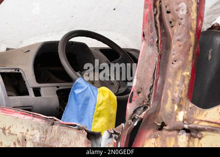 Un véhicule militaire tiré et le drapeau de l'Ukraine sur le volant se tient en Ukraine dans la rue, un véhicule militaire soufflé 2023 Banque D'Images