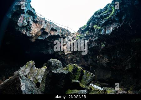 Grotte avec ouverture et lumière à travers. Marche à travers la grotte de lave en Islande Banque D'Images