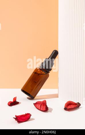 Sérum cosmétique vitamine C en flacon de verre brun avec pipette compte-gouttes sur fond blanc et orange pastel. Concept de cosmétiques de beauté. Soin naturel de la peau Banque D'Images