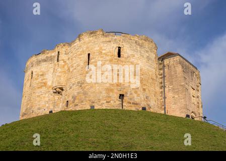 Une ancienne tour du 13th siècle est située sur un remblai de gazon. Une main courante surplombe le bâtiment et un ciel avec des nuages est au-dessus. Banque D'Images