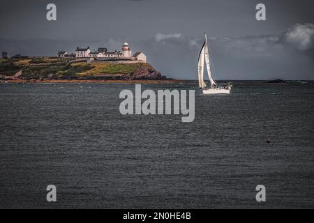 Bateau à voile devant le phare de Roche's point. Co Cork, Irlande Banque D'Images