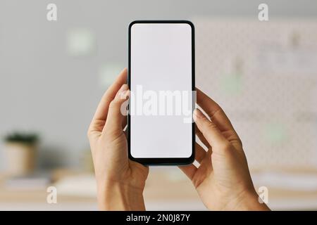 Gros plan des mains des femmes tenant le smartphone avec écran blanc Banque D'Images