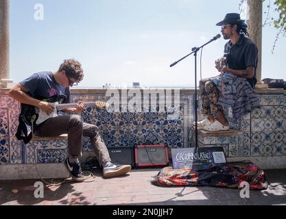 Deux musiciens de rue jouent de la guitare pour les touristes au mirador de santa lucia, dans le quartier horizontal d'Alfama à lisbonne, au Portugal Banque D'Images