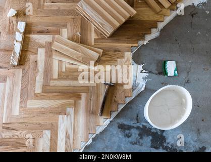 Vue de dessus des planches de parquet en installation à chevrons avec des outils, concept de plancher de maison Banque D'Images