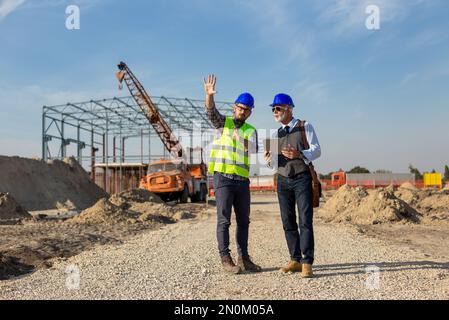 Deux ingénieurs satisfait à parler du site de construction avec structure de construction en arrière-plan Banque D'Images