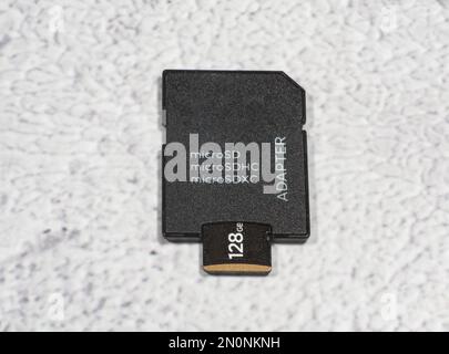 Vue de dessus de la carte mémoire microSD partiellement insérée dans l'adaptateur SD sur fond gris tacheté. Banque D'Images