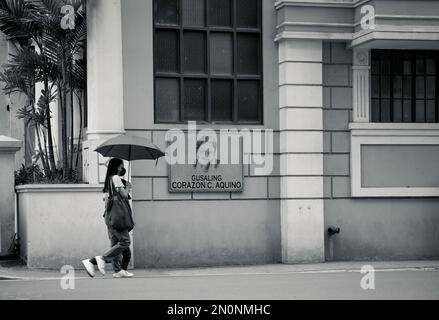 Une échelle de gris de personnes marchant sous un parapluie dans le quartier historique d'Intramuros à Manille, Philippines Banque D'Images