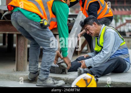 l'ingénieur a un accident où de l'acier tombe sur la jambe au travail, causant de graves blessures aux jambes. et obtenir l'aide de collègues dans la région sous constructi Banque D'Images