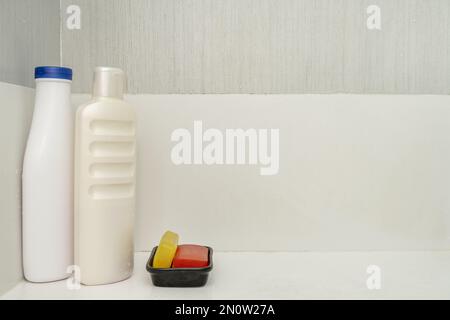 des bouteilles de shampooing et des barres de savon de glycérine aux couleurs vives à l'intérieur d'une salle de douche avec un plat blanc Banque D'Images