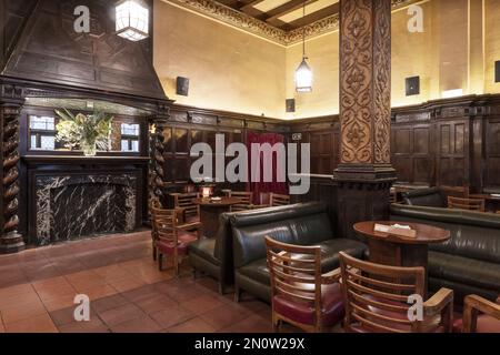 Salon d'un bar de style pub britannique avec canapés capitonnés en similicuir et grande cheminée Banque D'Images